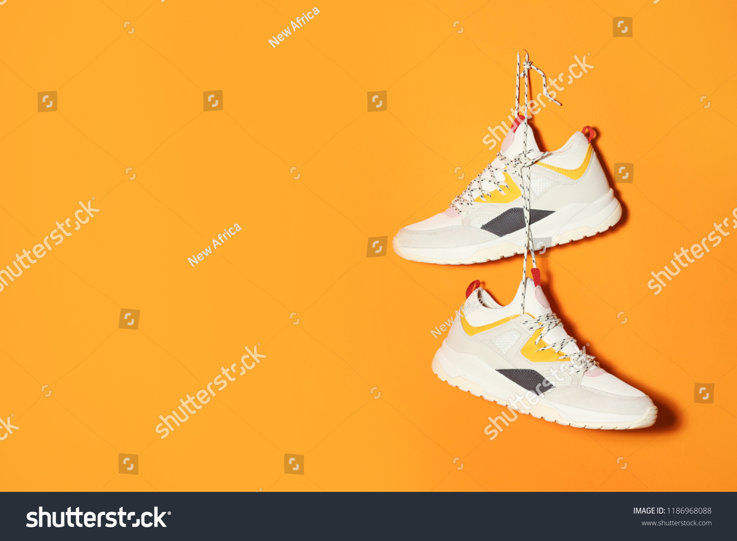 Pair of stylish sneakers hanging on color wall, space for text #1186968088