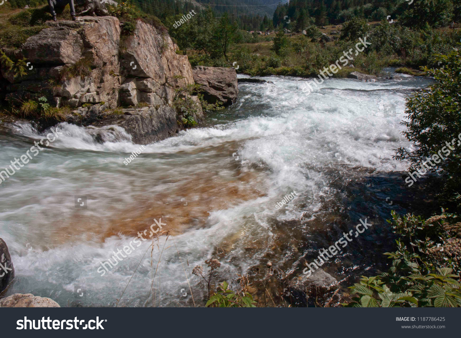A mountain stream flows with its impetuous waters between the rocks #1187786425
