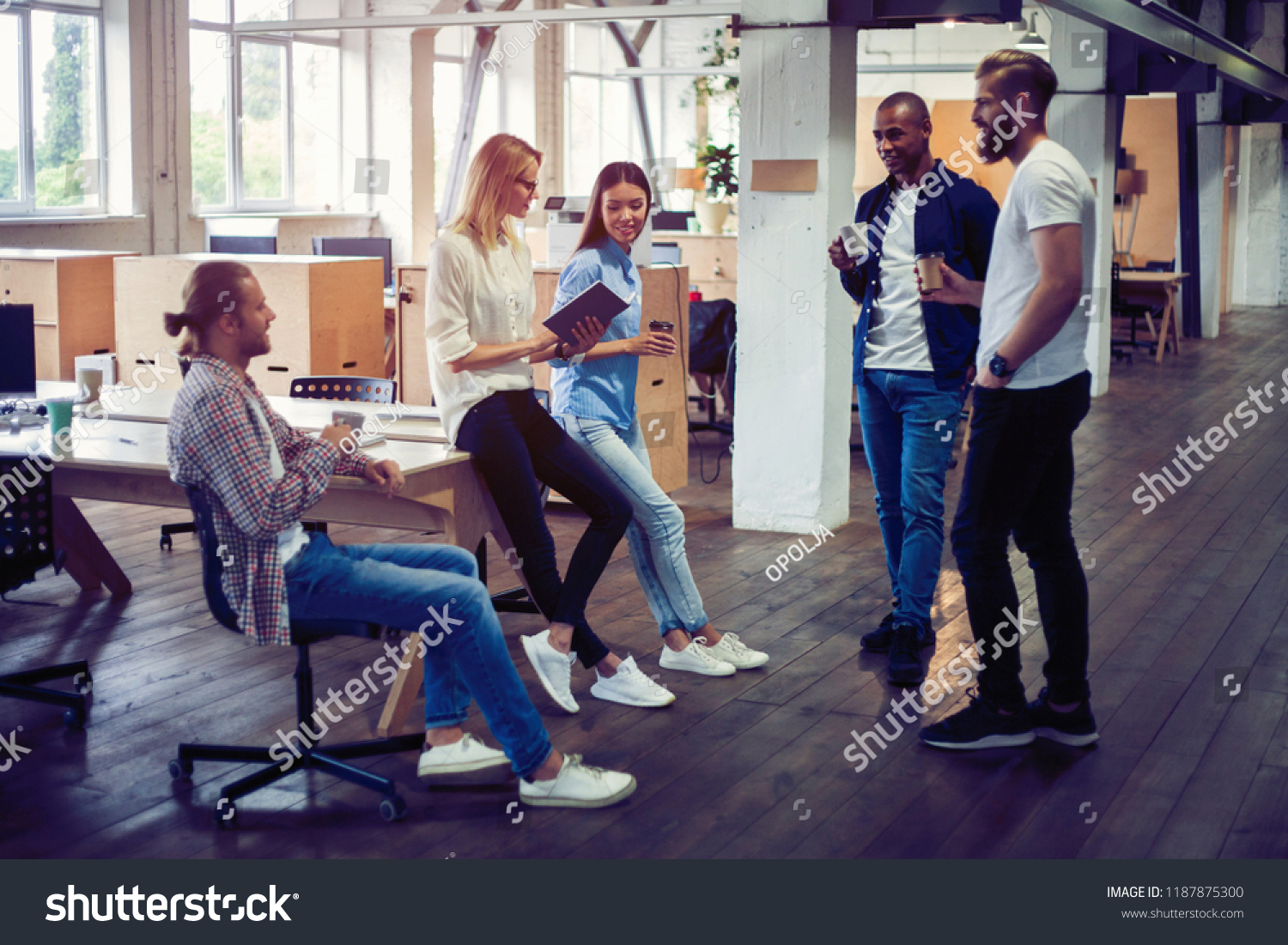 Happy to work together. Group of young business people communicating while working in the office #1187875300