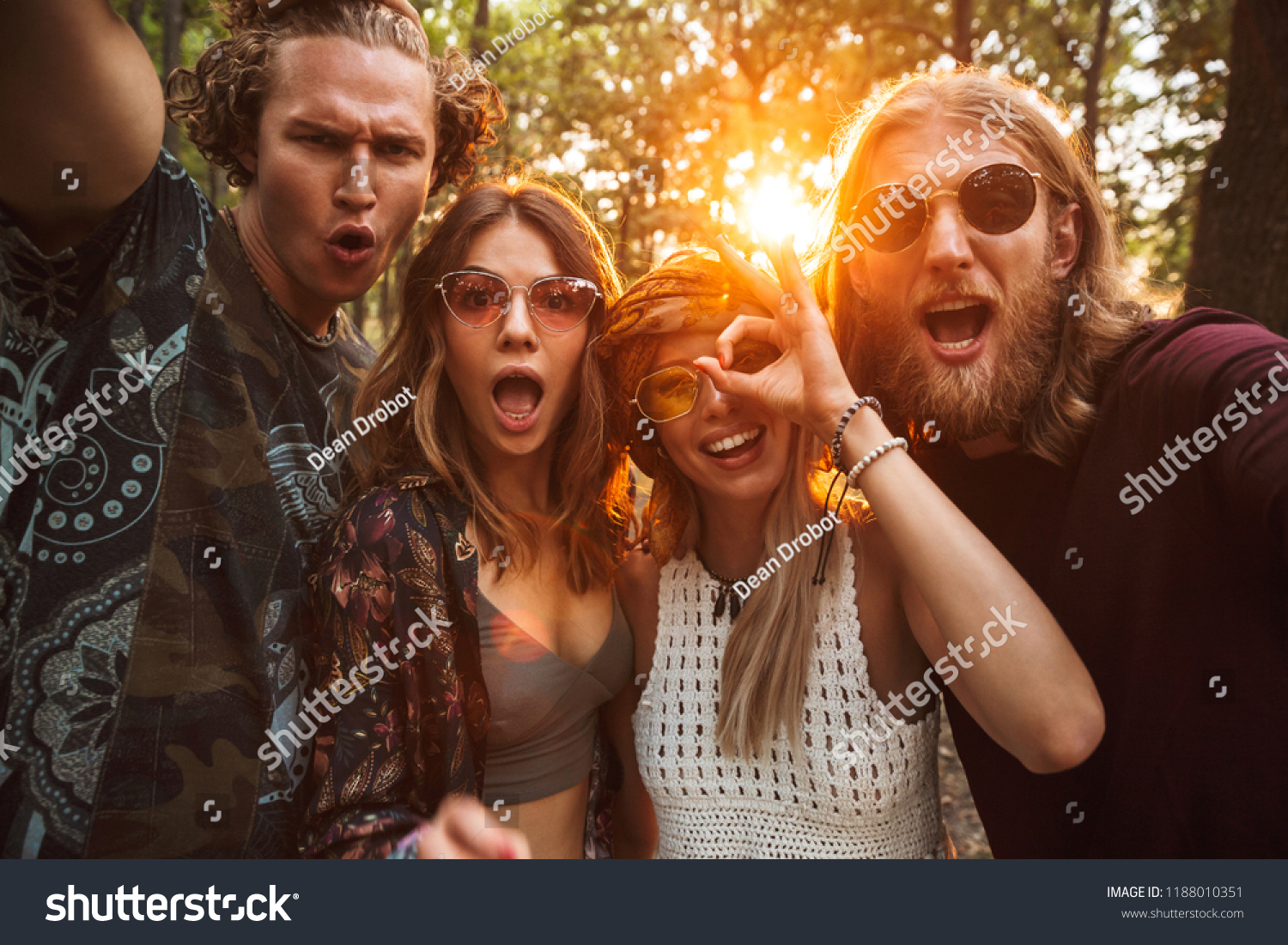 Photo of cheerful hippies men and women smiling and taking selfie in forest #1188010351