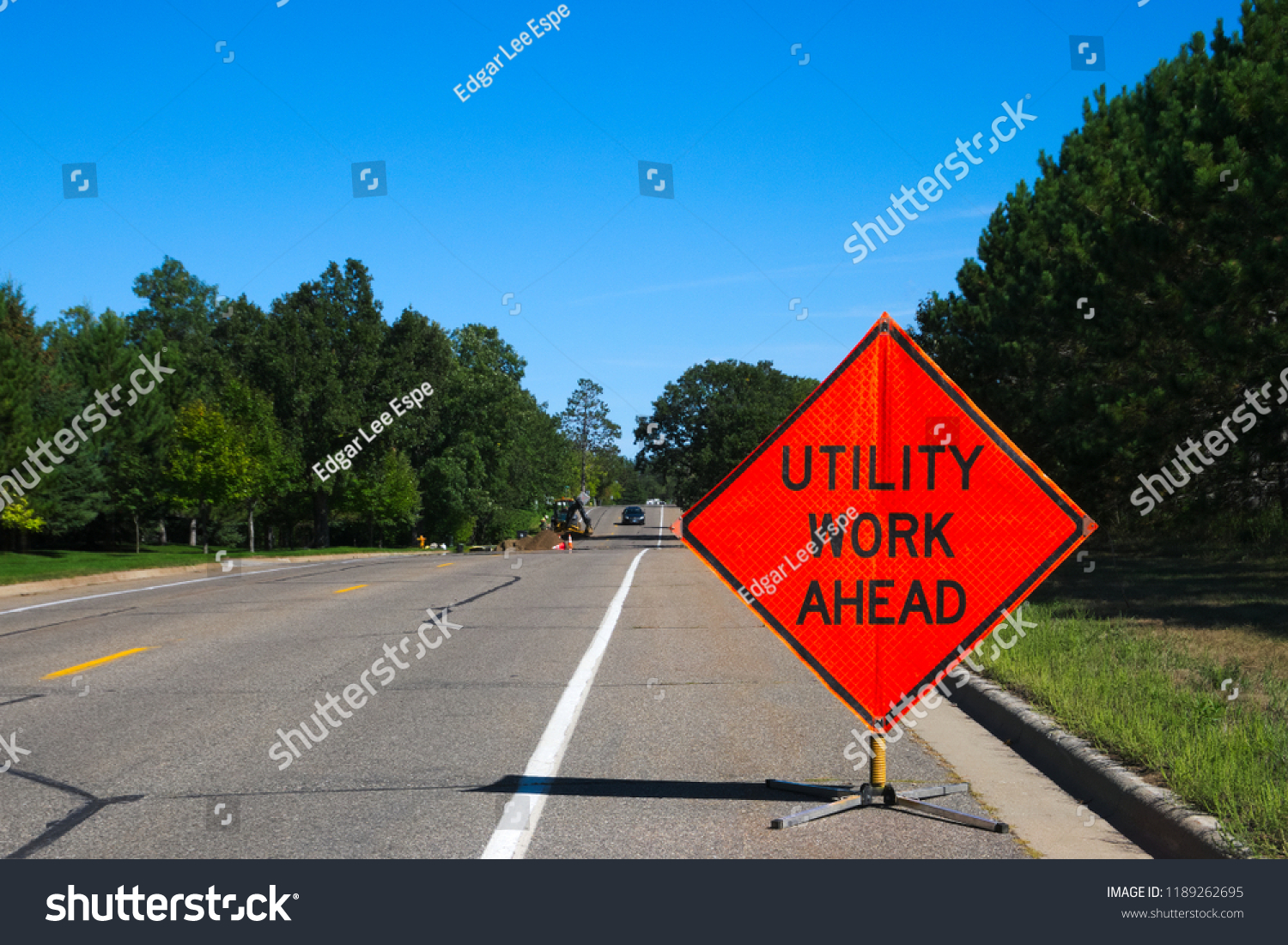 Utility Work Ahead sign with service vehicle down the street #1189262695
