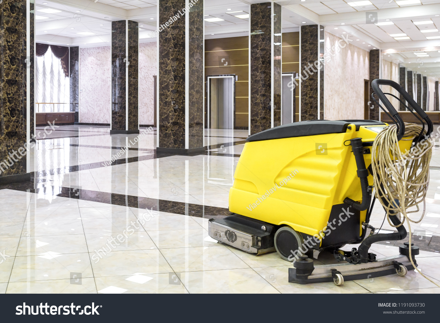 Cleaning machine in empty office lobby, yellow vacuum equipment is on clean shiny marble floor in commercial building. Concept of professional cleaning, maintenance and care service. #1191093730