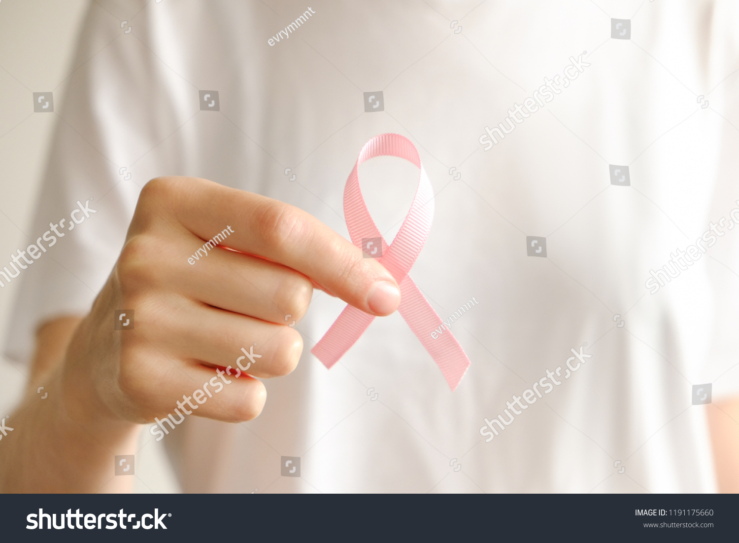 Woman in blank white t-shirt holding pink colored ribbon, international symbol of breast cancer awareness & moral support for survivors. Isolated background, copy space, close up, top view fat lay. #1191175660