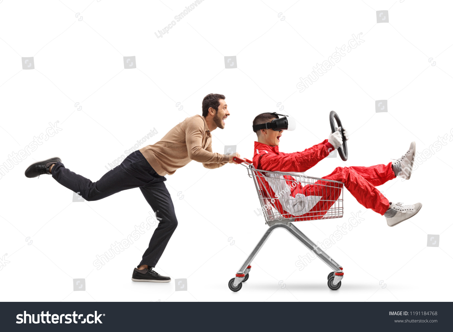 Teenager in a racing suit with VR googles in a shopping cart being pushed by a young man isolated on white background #1191184768