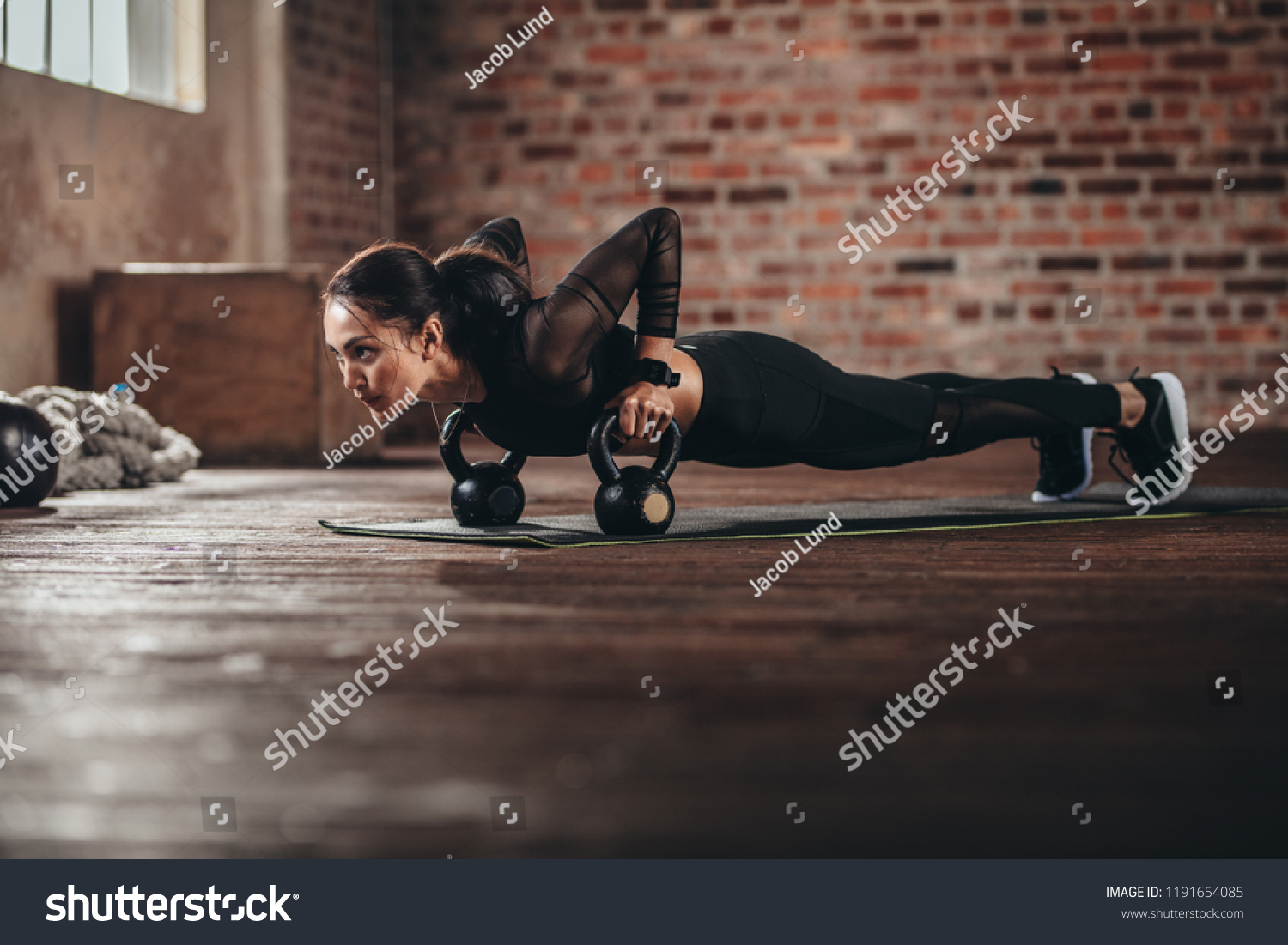 Fit female doing intense core workout in gym. Young woman doing push up exercise on fitness mat in health club. #1191654085