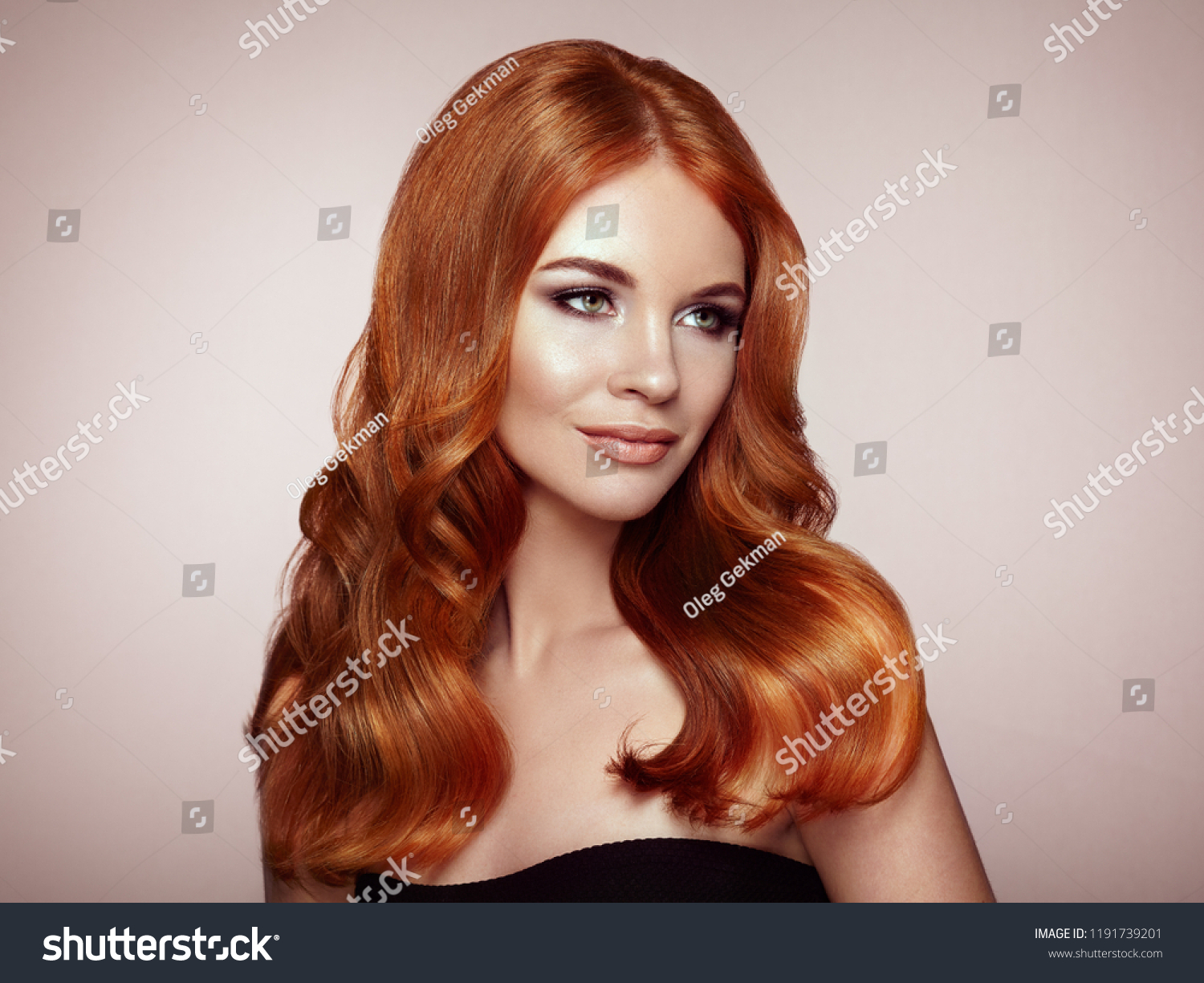 Redhead Girl with Long Healthy and Shiny Curly Hair. Care and Beauty. Beautiful Model Woman with Wavy Hairstyle. Make-Up and Black Dress #1191739201