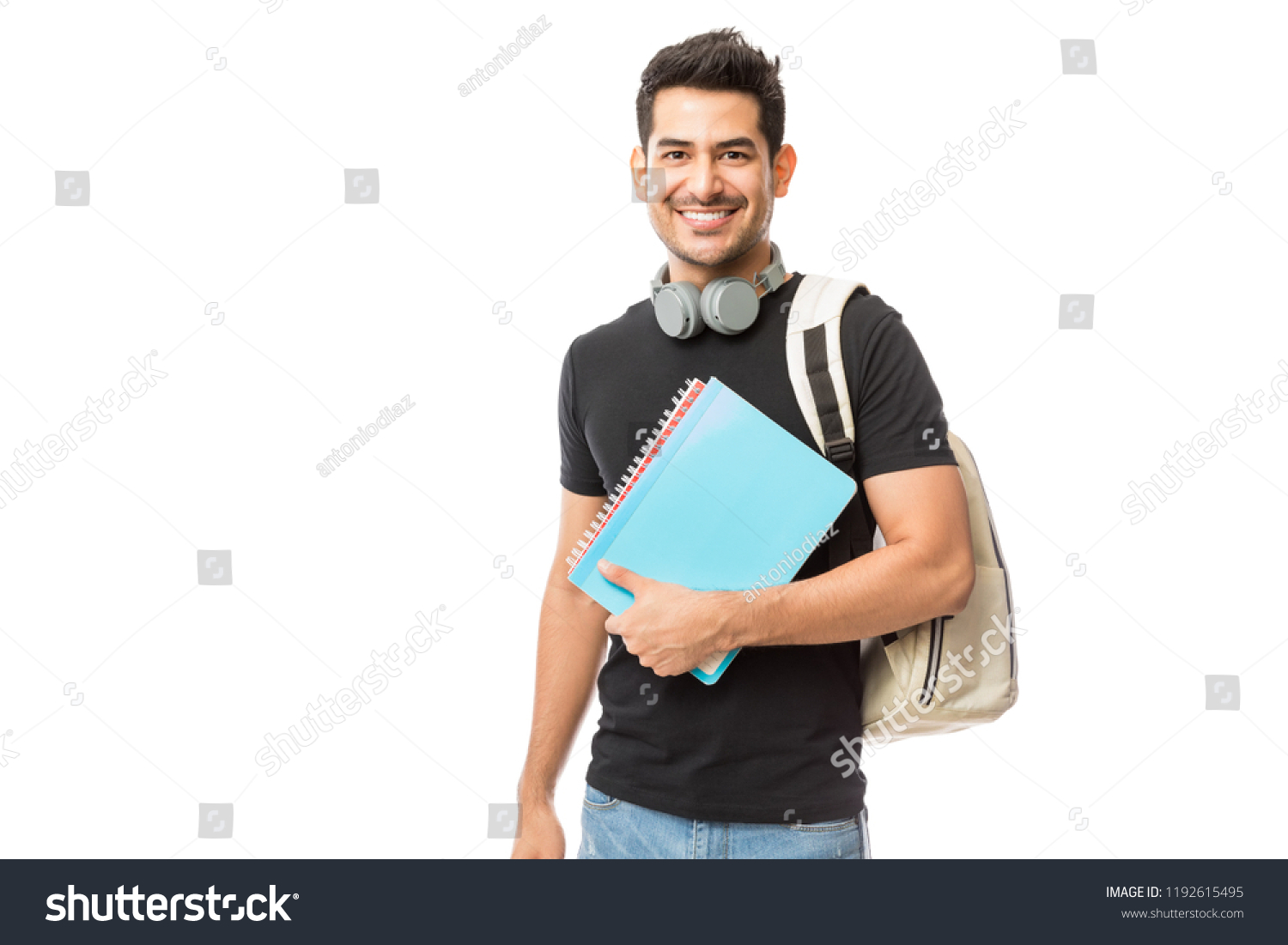 Portrait of smiling young college student with books and backpack against white background #1192615495