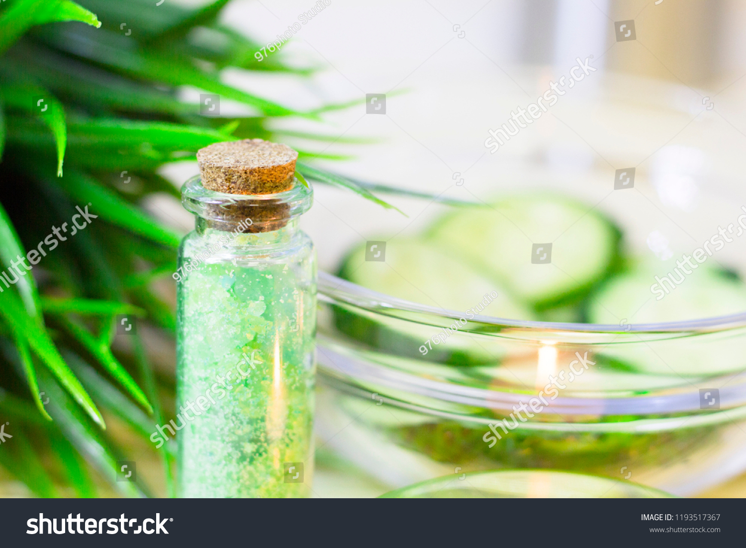 Cucumber home spa and hair care concept. Sliced cucumber, bottles of oil, bathroom towel. Straw light background. Closeup #1193517367