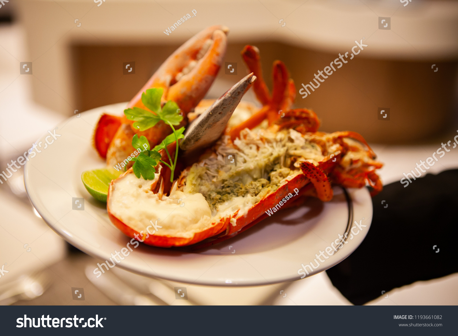 Simple yet delicious. Hot and freshly baked halved Lobster with butter. Fresh, juicy, tasty and flavorful bright red Maine Lobster or American lobster on a hand of waitperson, ready to be served. #1193661082