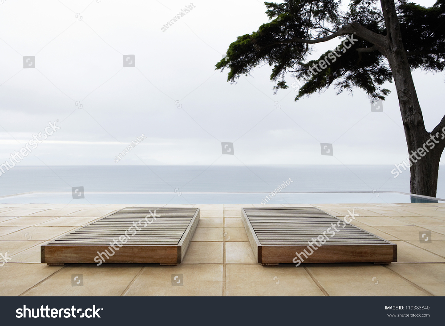 Two sun beds by infinity pool overlooking sea #119383840