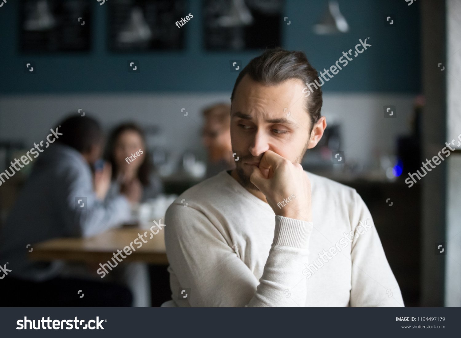 Upset millennial outsider feel offended lack company, young outcast guy suffer from discrimination, jealous of friends hang out together in café, envious male loner depressed sit alone in coffeeshop #1194497179