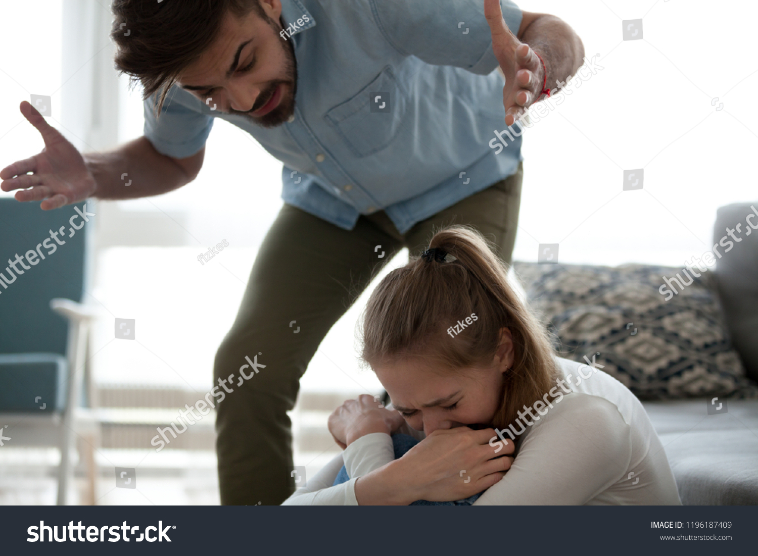 Unhappy crying frightened woman and aggressive man quarrelling at home. Angry husband emotionally arguing screaming shouting to scared wife psychological emotional abuse and domestic violence concept #1196187409
