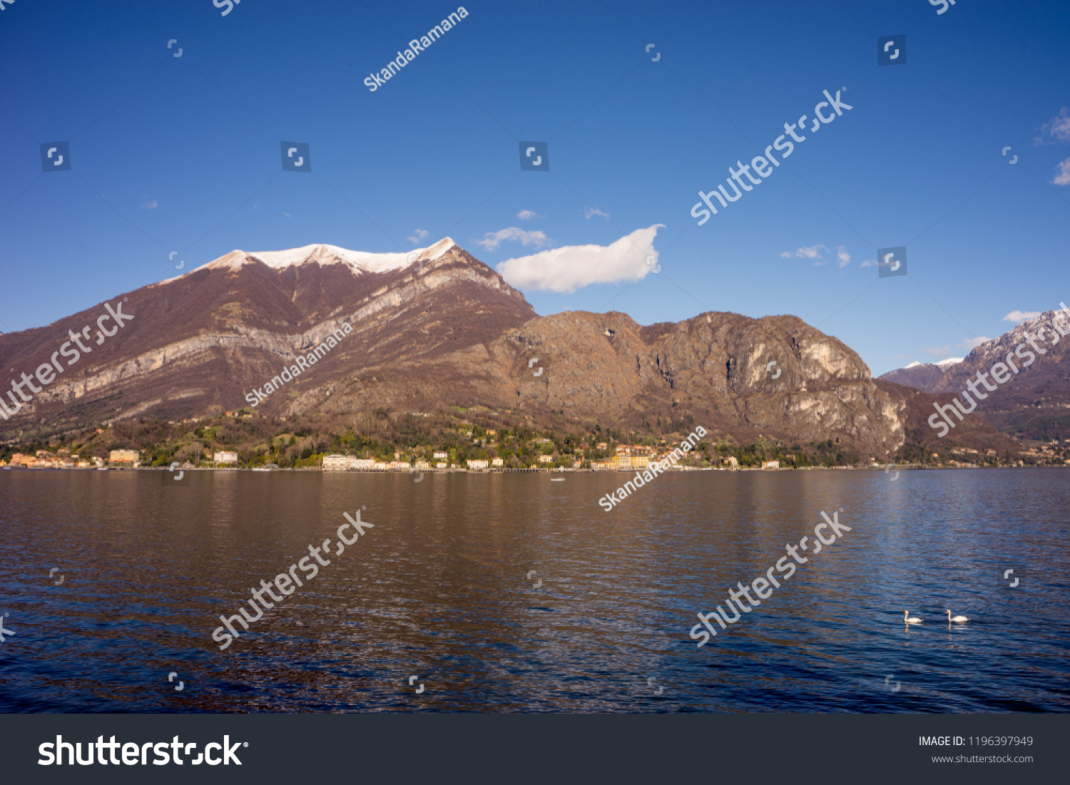 Italy, Bellagio, Lake Como, SCENIC VIEW OF SNOWCAPPED MOUNTAINS AGAINST BLUE SKY with swans on lake #1196397949