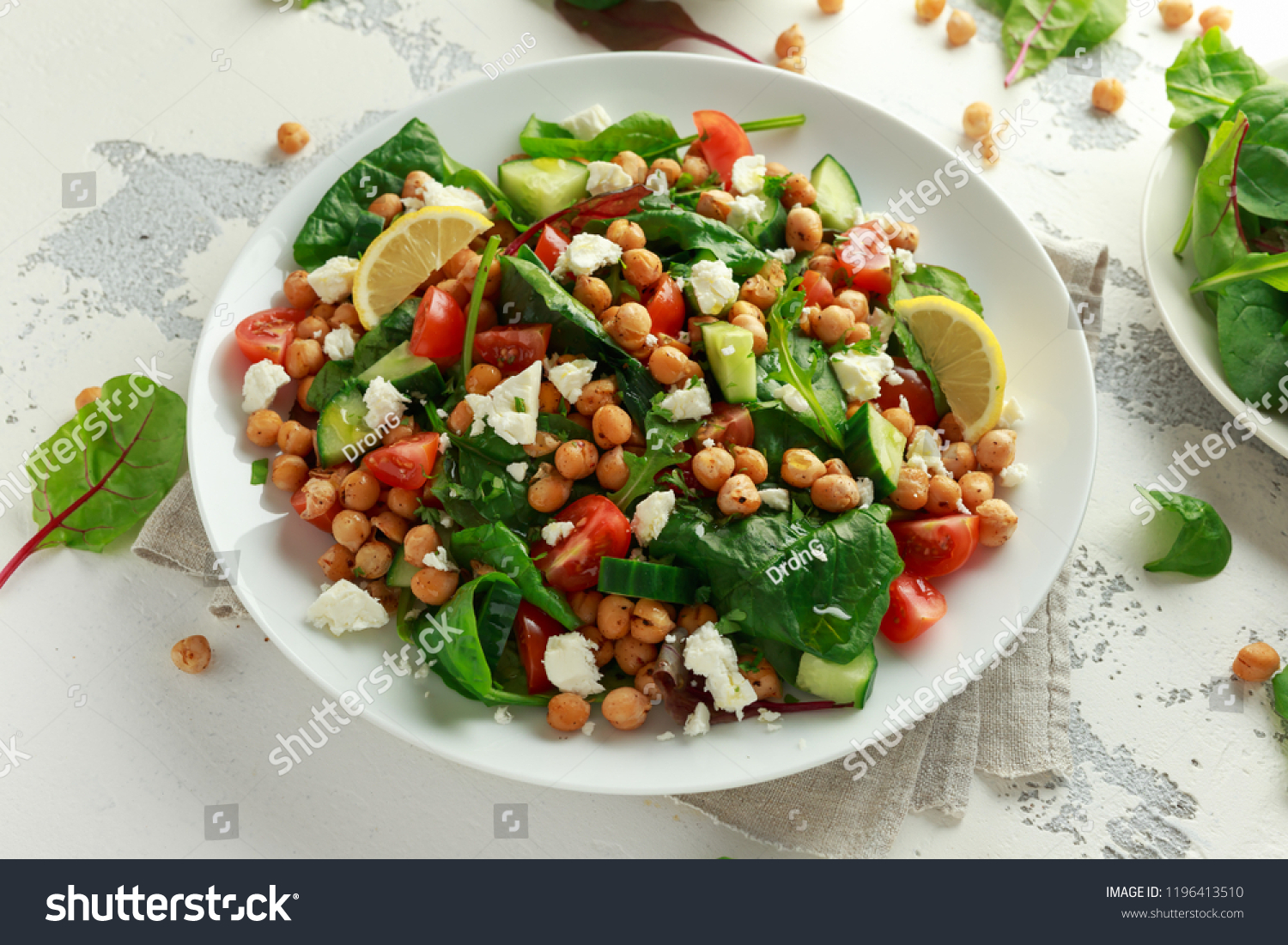 Chickpeas Salad with cucumber, tomatoes, feta cheese and green mix in a white plate. healthy food. #1196413510