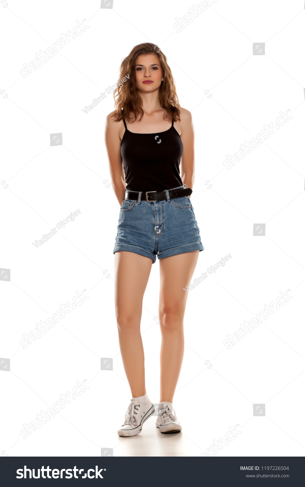 Young pretty woman in short jeans standing on white background #1197226504