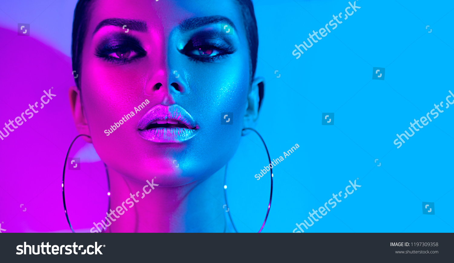 High Fashion model metallic silver lips and face woman in colorful bright neon uv blue and purple lights, posing in studio, beautiful girl, glowing make-up, colorful make up. Glitter Vivid neon makeup #1197309358