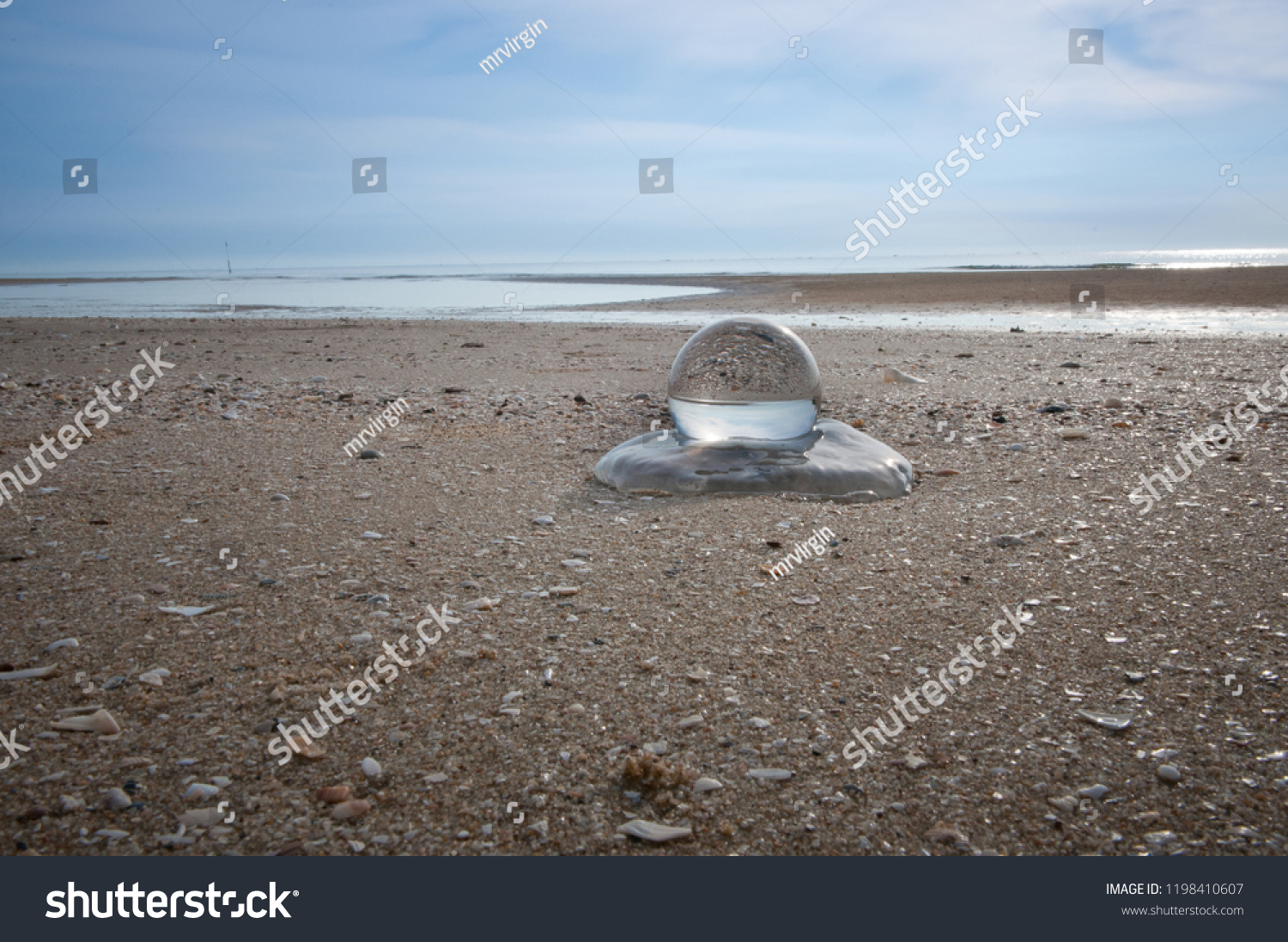 Beautiful Tropical Landscape seen through a Glass Orb. Glass orb by the sea and beach with waves crashing on shore. #1198410607