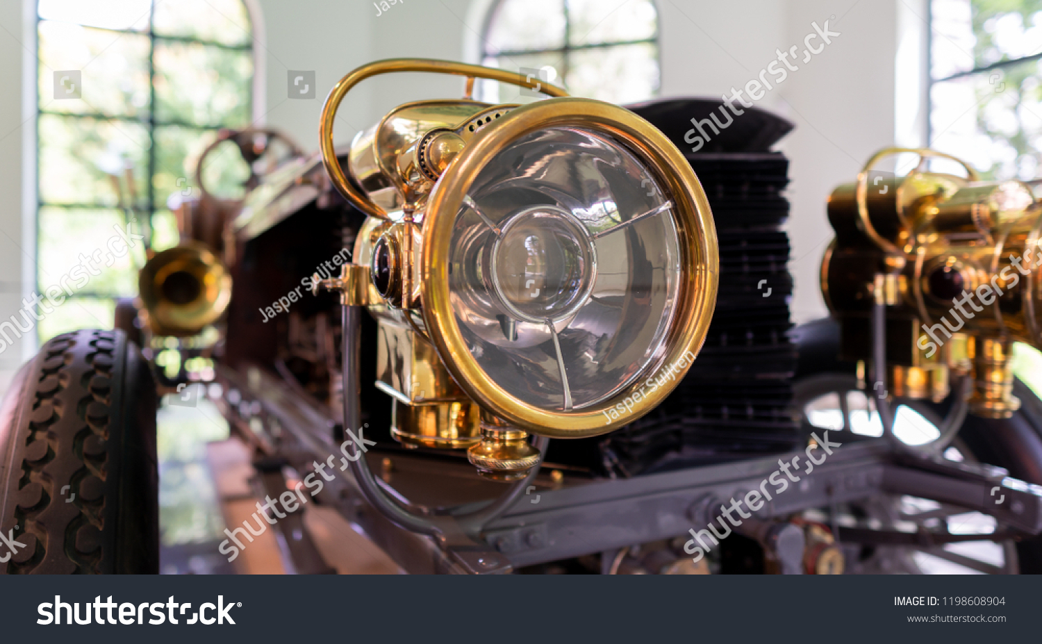 Vintage antique brass old timer car headlight. Auto head lamp. Shallow depth of field. Close up of vintage vehicle head light. #1198608904