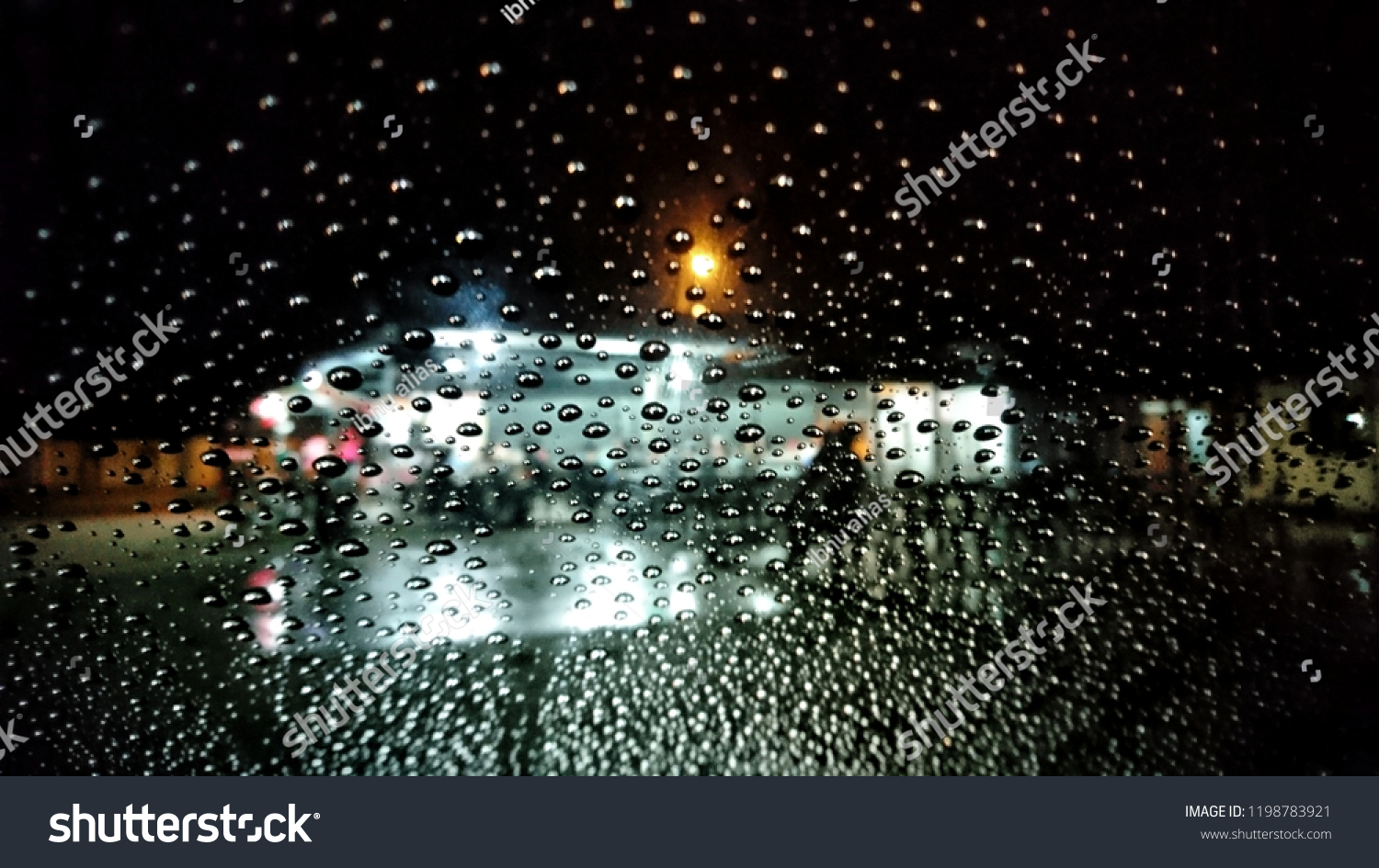 Wet the window with the background of the autumn night city. Selective focus.  #1198783921