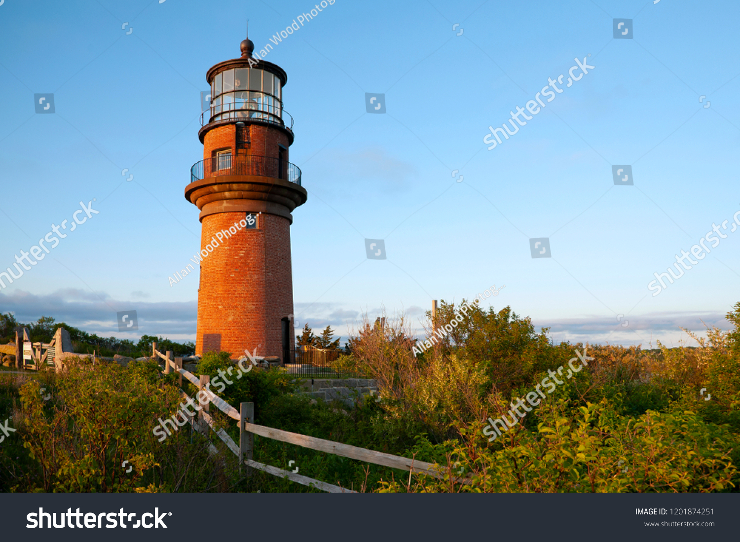 Wooden fence leads to the large brick tower of Aquinnah lighthouse, also referred to as Gay Head light, on a late summer day on Martha’s Vineyard island in Massachusetts. #1201874251