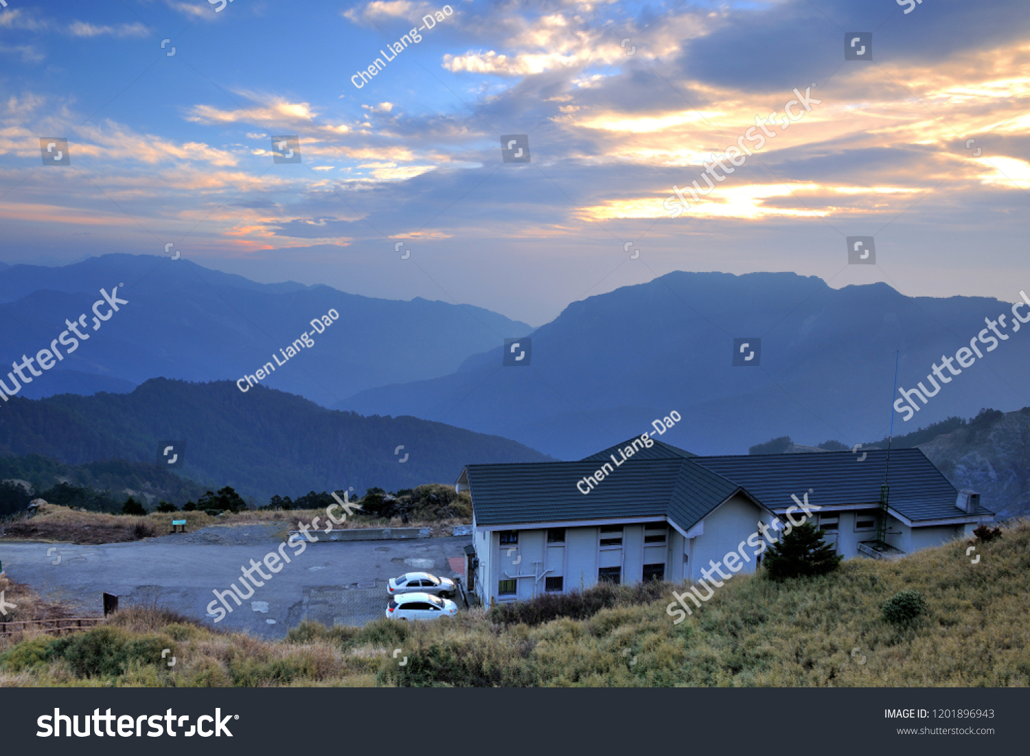 On the high mountains of the continuous mountains, the blue roofs of the white walls of the building, the blue sky has orange clouds. #1201896943