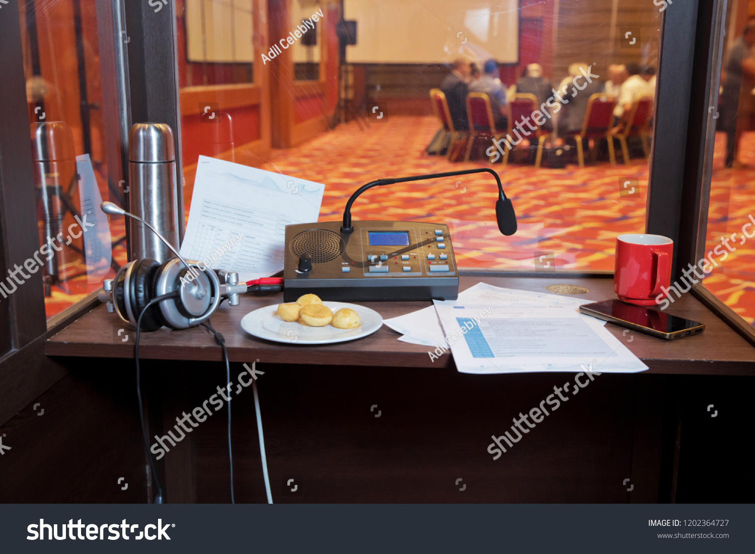 translators cubicle . interpreting - Microphone and switchboard in an simultaneous interpreter booth . Soft focus of wireless Conference microphones and notebook in a meeting room. #1202364727