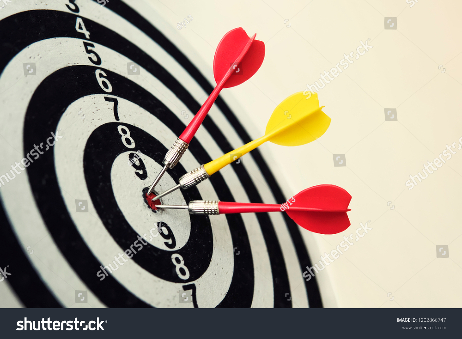 Side view of a dartboard with three darts in the bull's eye. Well-aimed dart throwing. Triple bull's-eye hit. Three well-made dart throws. Successful attempts. To attempt difficult task. Darts ace #1202866747