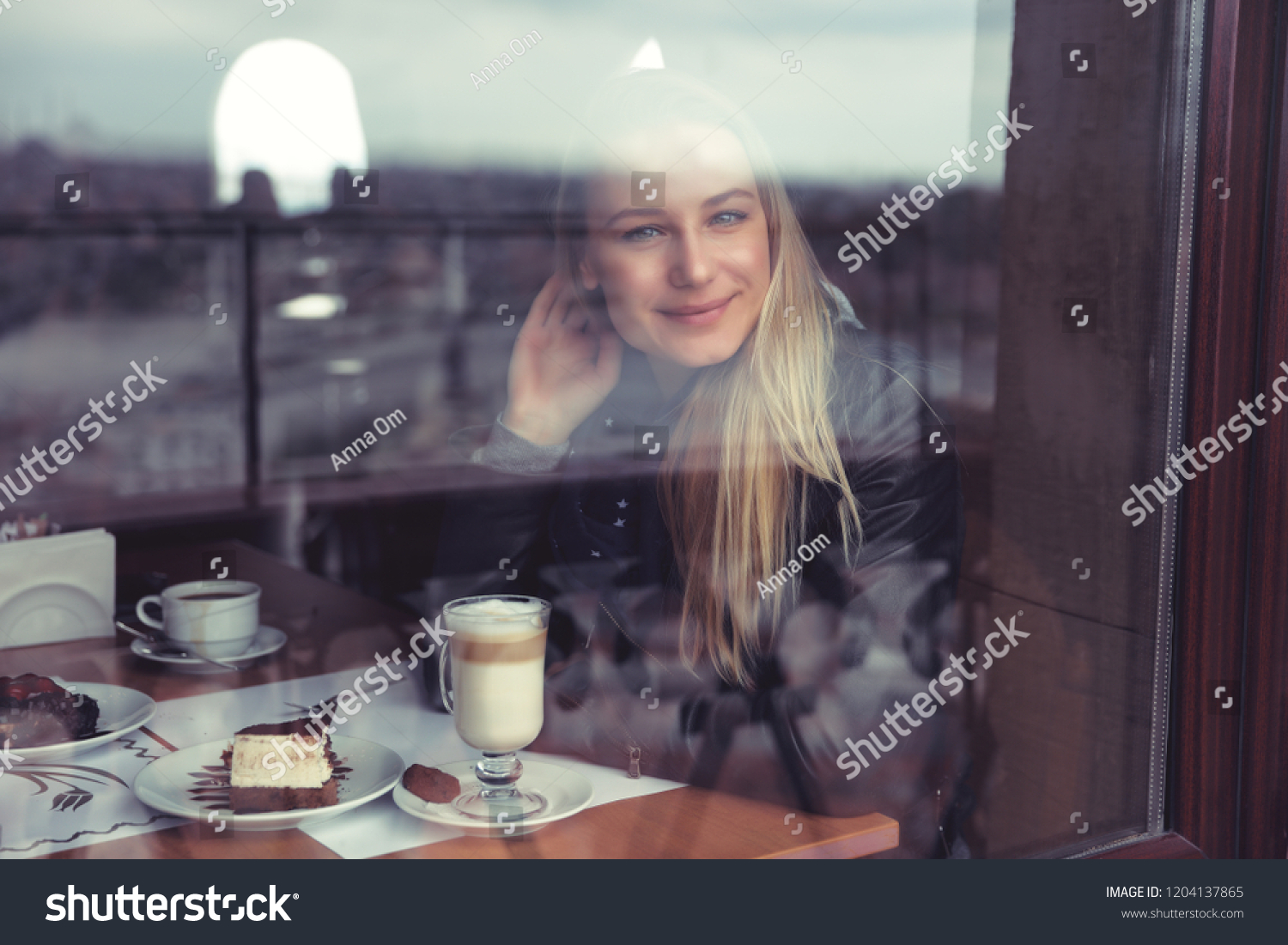 Nice female in cafe in warm cozy atmosphere, enjoying view through the window, casual urban life of young people #1204137865