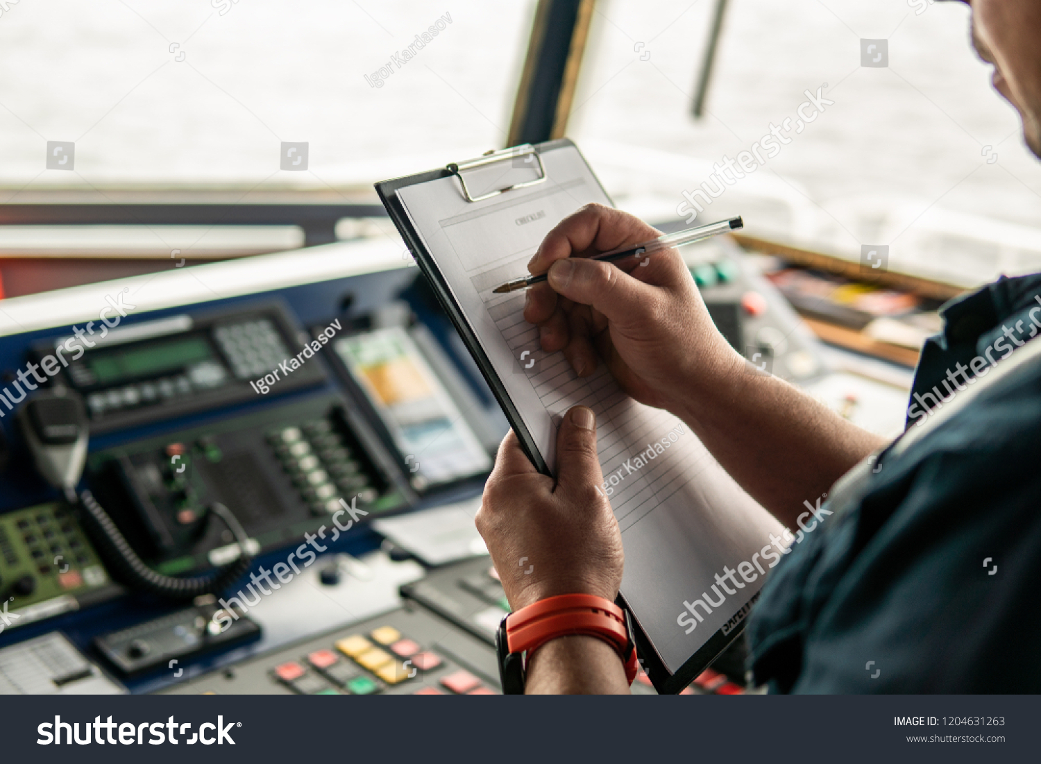 Marine navigational officer or chief mate on navigation watch on ship or vessel. He fills up checklist. Ship routine paperwork #1204631263