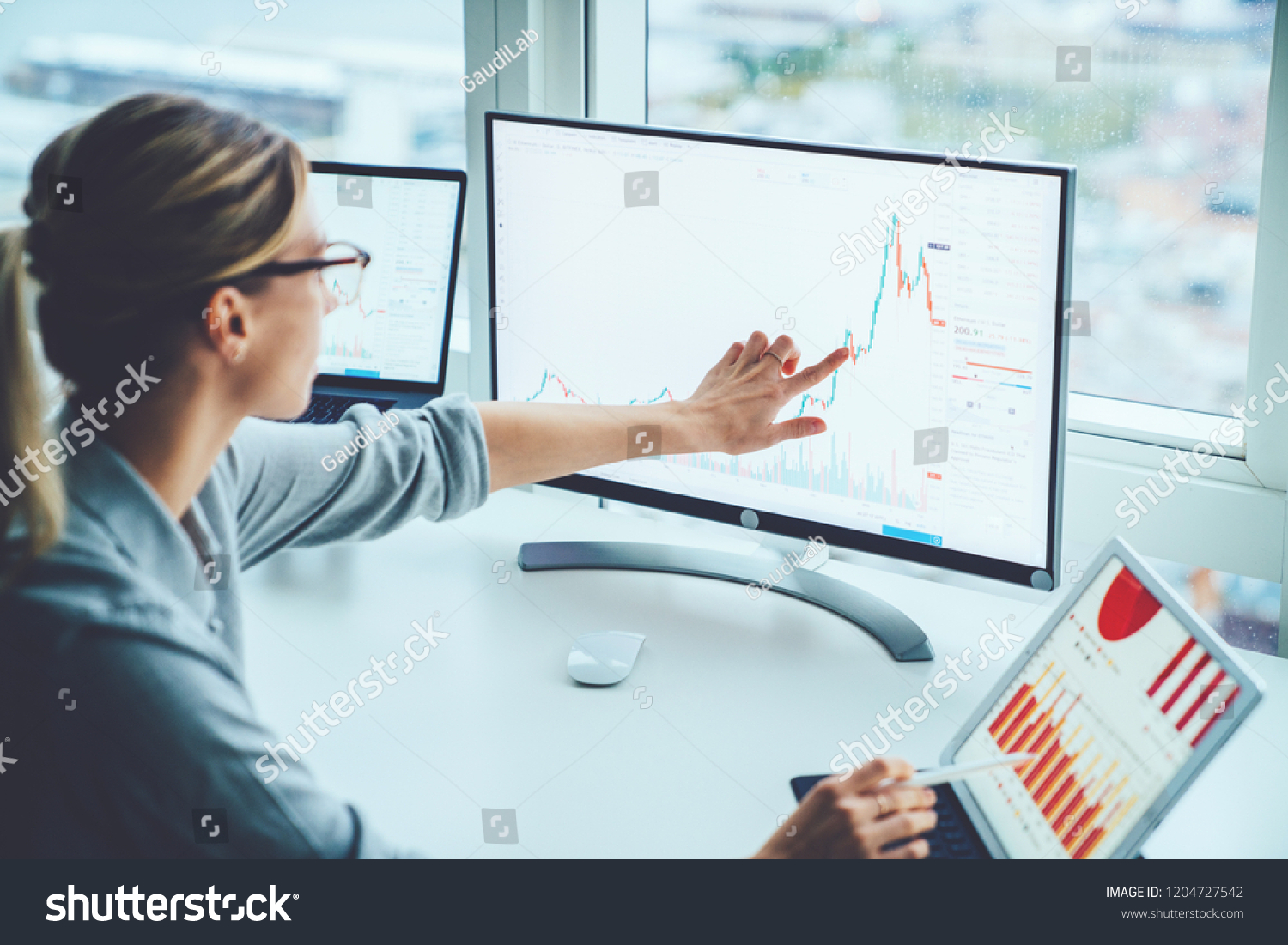 Business woman study financial market to calculate possible risks and profits.Female economist accounting money with statistics graphs pointing on screen of computer at desktop. Quotations on exchange #1204727542