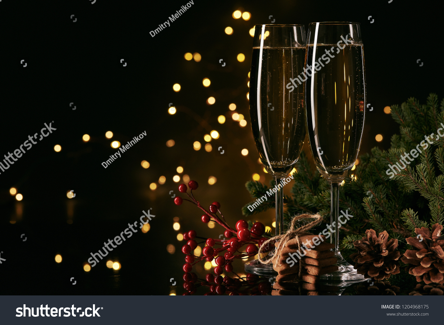 Two glasses with champange, fir tree branch and gingerbread cookies on a dark background with LED lights garland. New year and Christmas. #1204968175