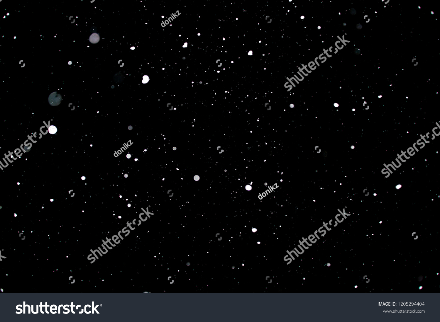 Snowstorm texture. Bokeh lights on black background, shot of flying snowflakes in the air #1205294404
