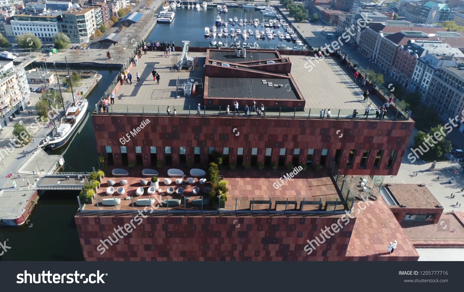 Aerial photo tall building roof in Belgium Antwerp located along the river Scheldt in Eilandje district showing people enjoying the beautiful weather of summer day #1205777716