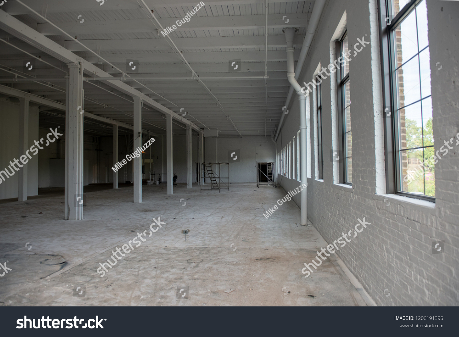 White walled abandoned warehouse under construction with white timber pillars, wooden ceilings and concrete floors #1206191395