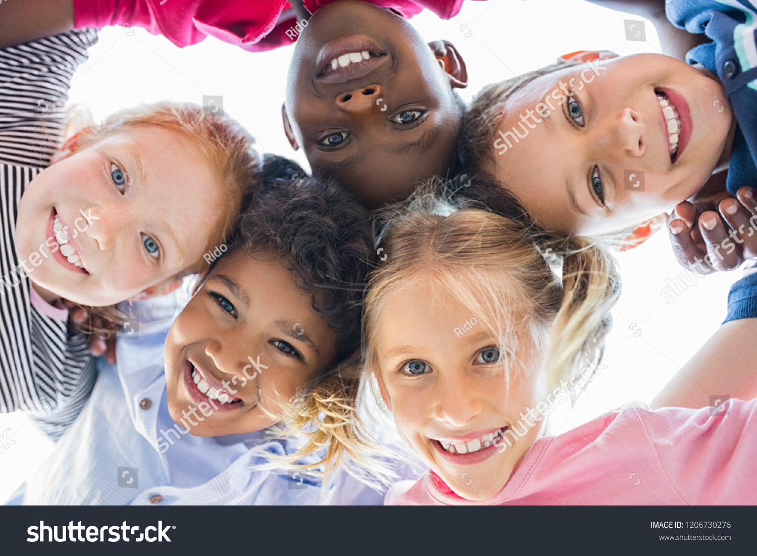 Closeup face of happy multiethnic children embracing each other and smiling at camera. Team of smiling kids embracing together in a circle. Portrait of young boy and pretty girls looking at camera. #1206730276