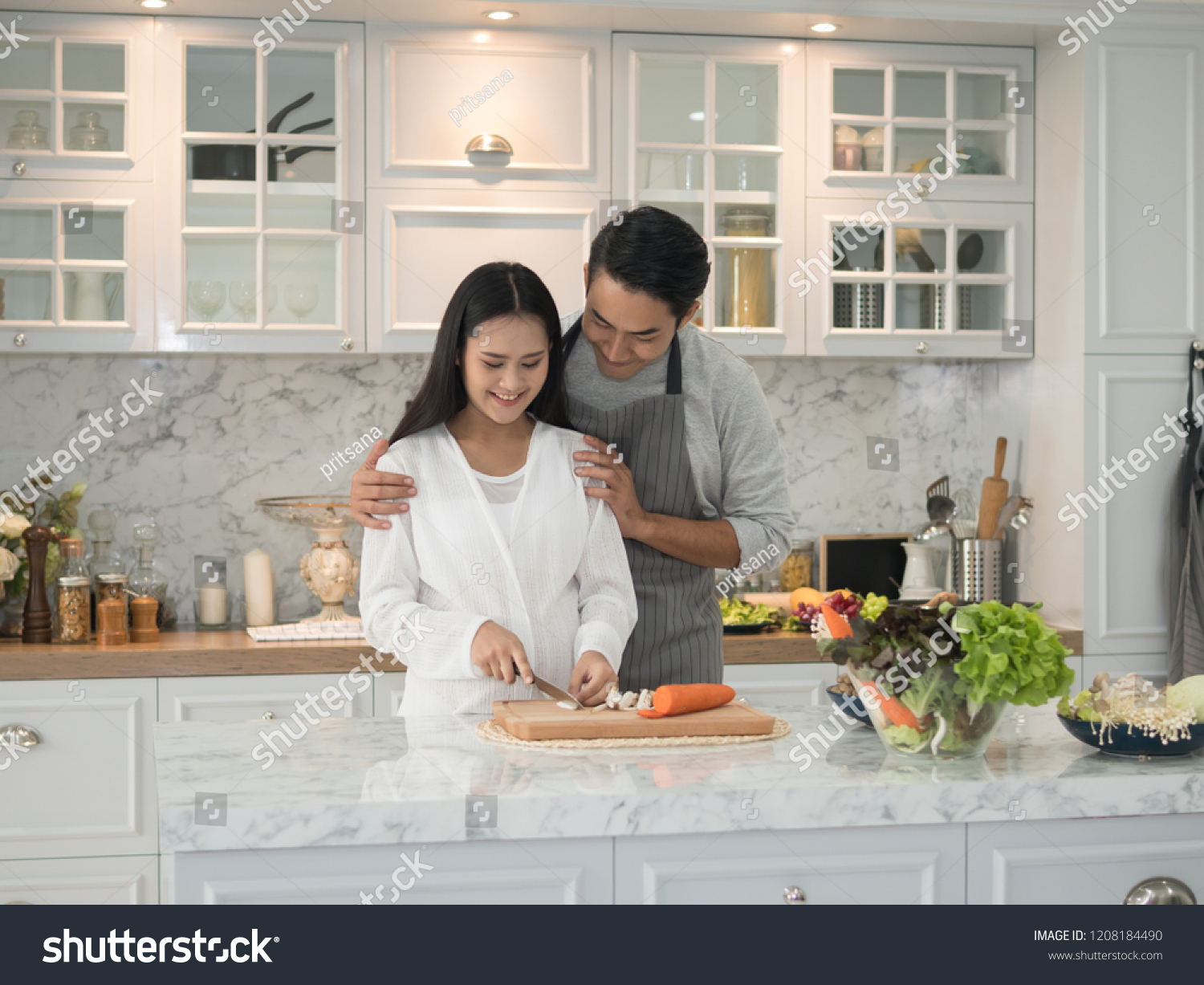 Young asian expecting pregnant couple cooking together in the kitchen at home. Pregnant woman preparing food with her husband.
 #1208184490