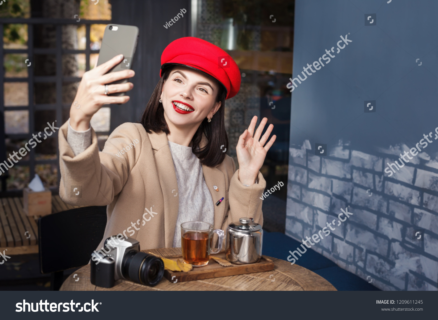 Beautiful smiling girl sitting in a cafe and using a smartphone #1209611245