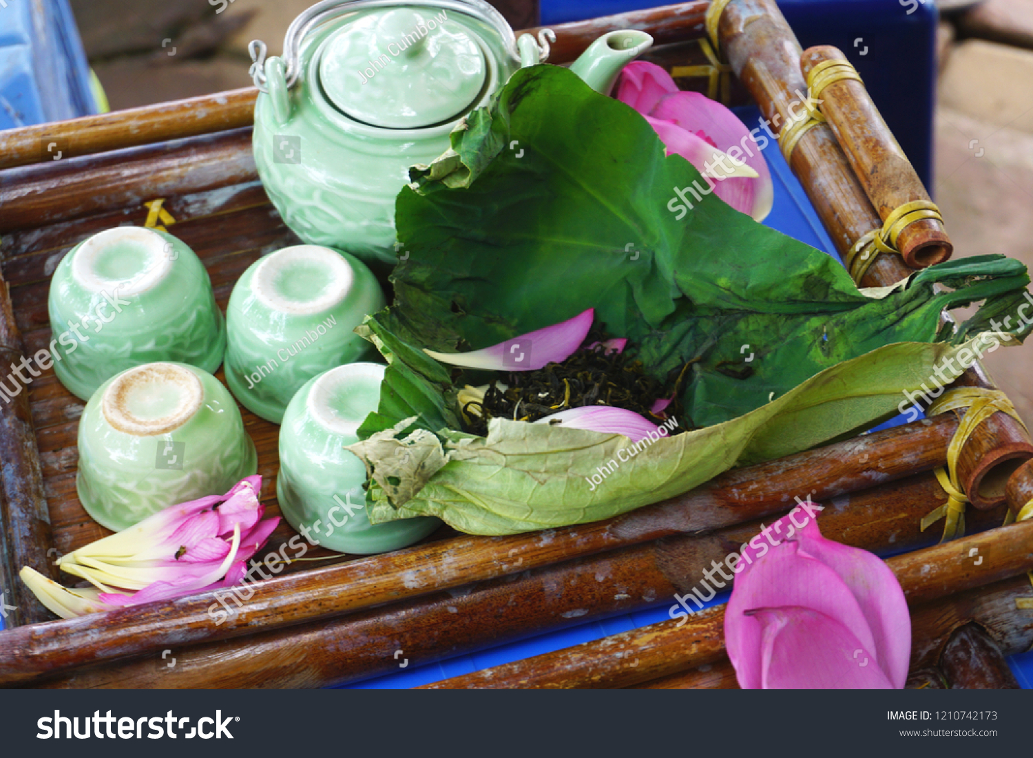 Vintage antique celadon glazed porcelain tea set with lotus flower tea on a lotus leaf and pink lotus petals on a bamboo tray #1210742173