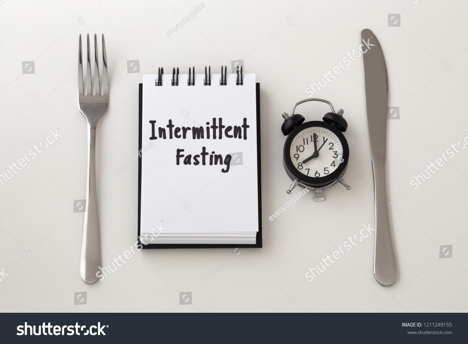 Intermittent fasting word on notepad with clock, fork and knife, weight loss plan #1211249155
