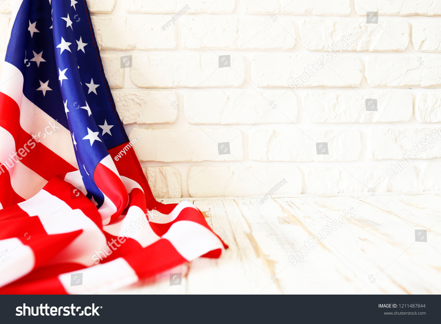 Close up of ruffled American flag over lofty white brick wall with a lot of copy space. Patriotic background for national holidays in United States of America. Stars and stripes. #1211487844