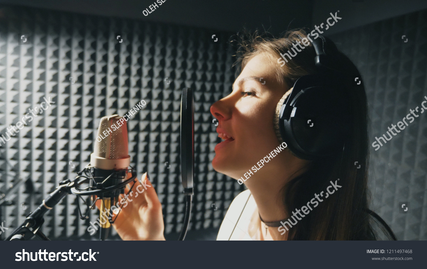 Profile of beautiful girl singing in sound studio. Young female singer emotionally recording new song. Woman sings to microphone. Working of creative musician. Show business concept. Slow motion. #1211497468