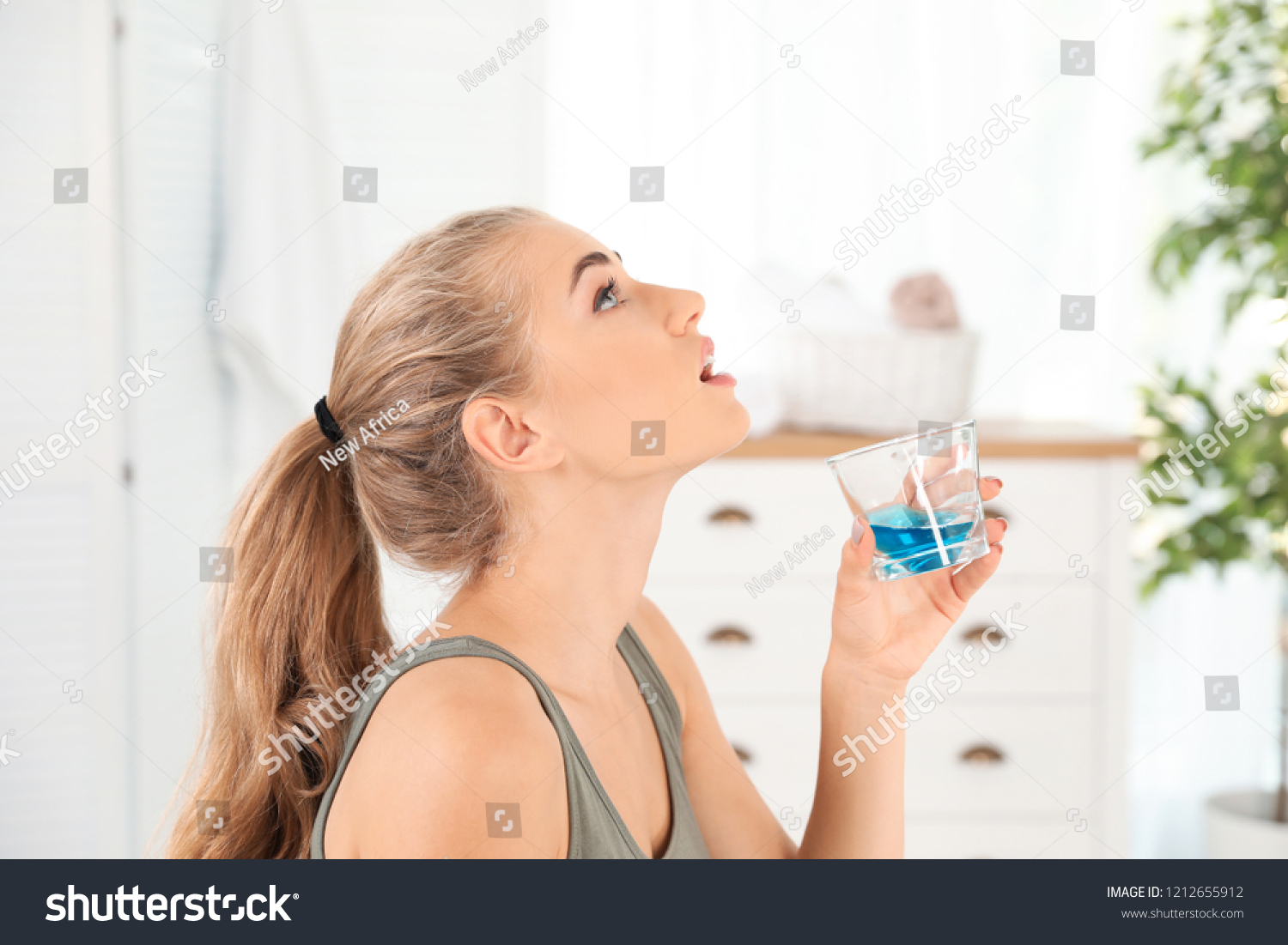 Woman rinsing mouth with mouthwash in bathroom. Teeth care #1212655912
