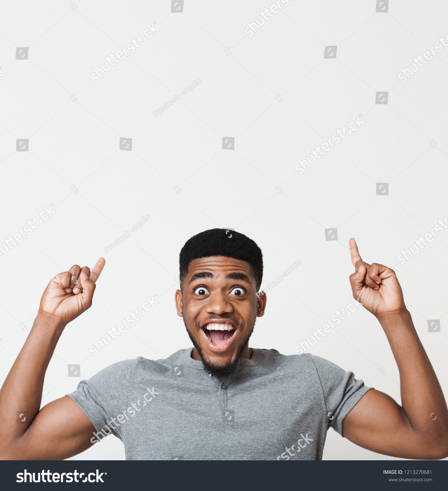 Excited african-american man having an idea and pointing two fingers up at copy space, white studio background #1213270681