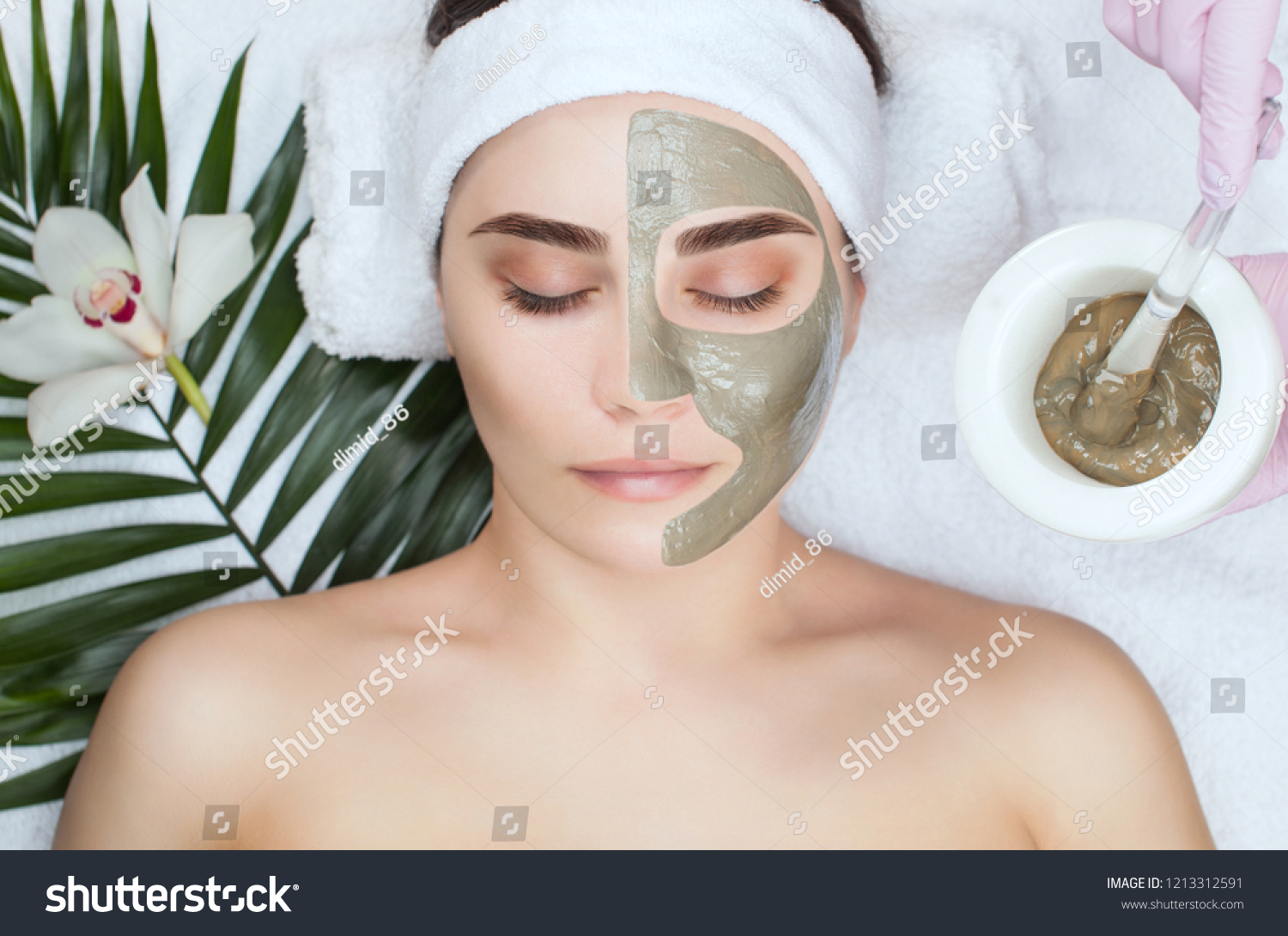 The procedure for applying a mask from clay to the face of a beautiful woman. Spa treatments and care of the face in the beauty salon. #1213312591