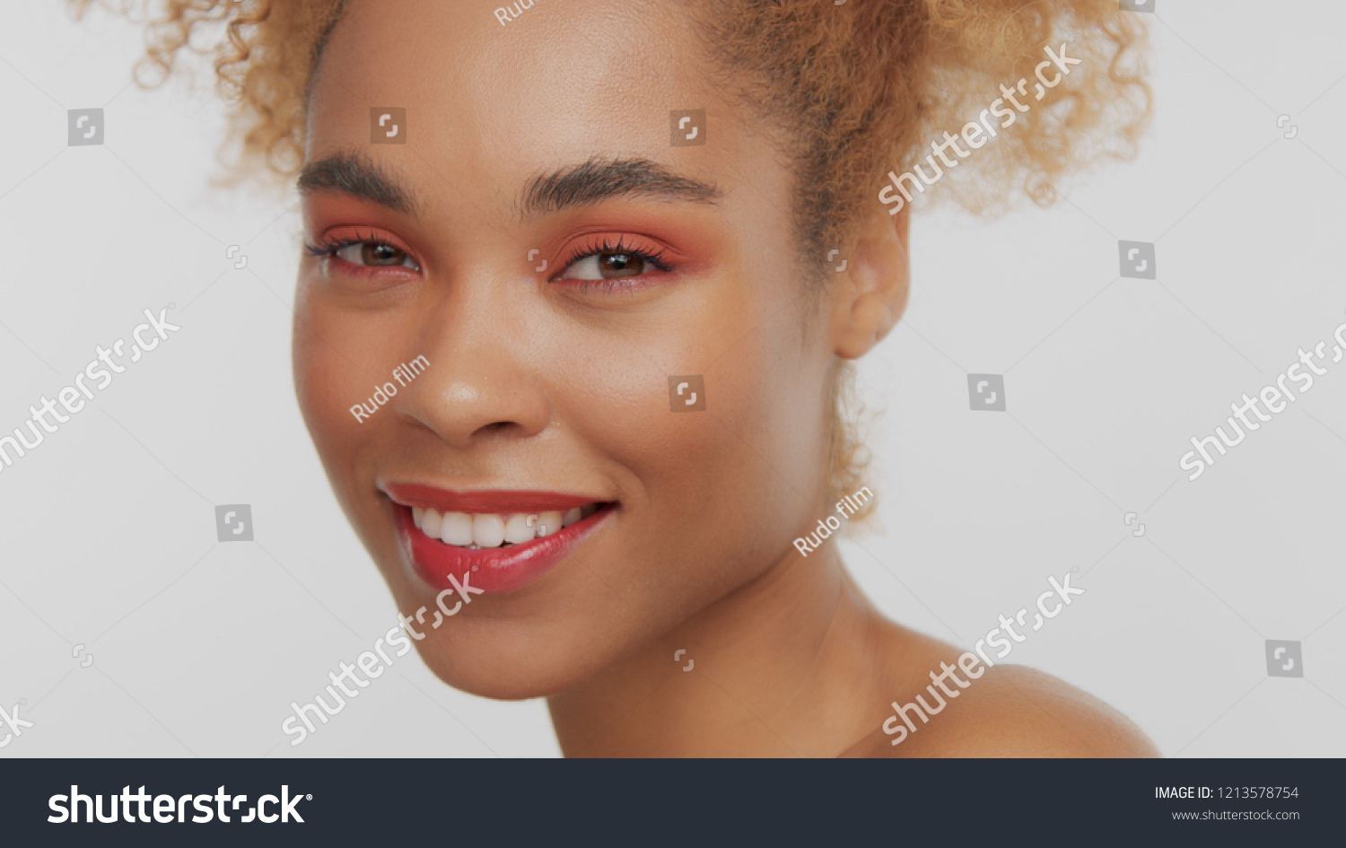closeup portrait of mixed rase woman with red makeup in studio close up smiling and watching to the camera #1213578754