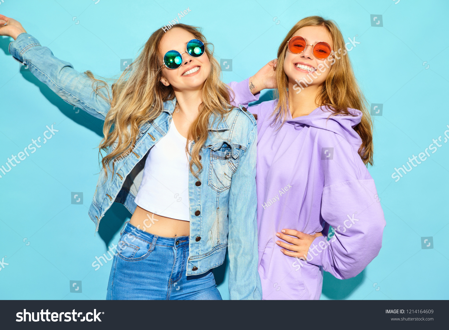 Two young beautiful blond smiling hipster girls in trendy summer clothes. Sexy carefree women posing near blue wall in sunglasses. Positive models going crazy #1214164609