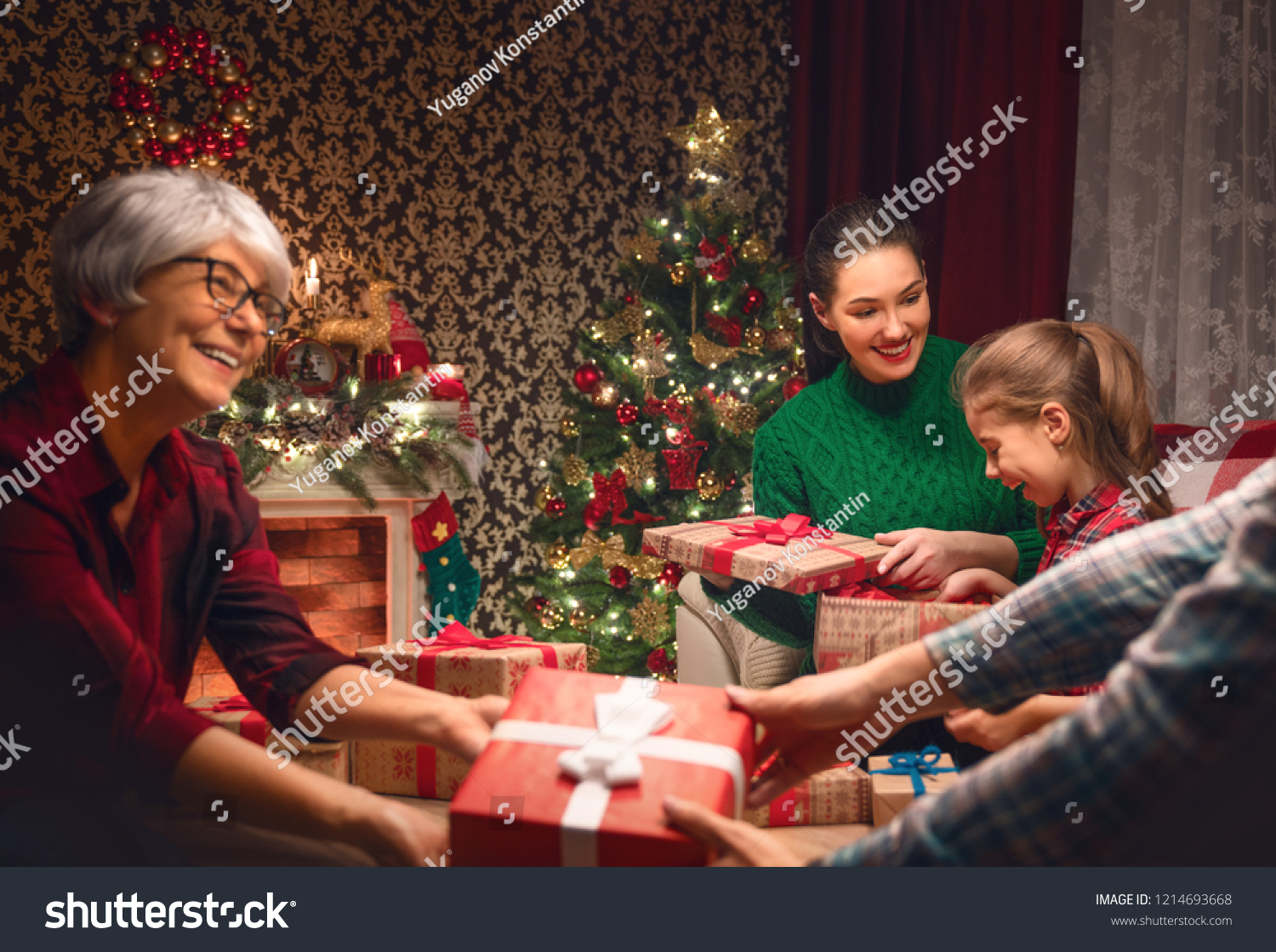 Merry Christmas and Happy Holidays! Grandma, mum, dad and child exchanging gifts. Parents and daughter having fun near tree indoors. Loving family with presents in room. #1214693668