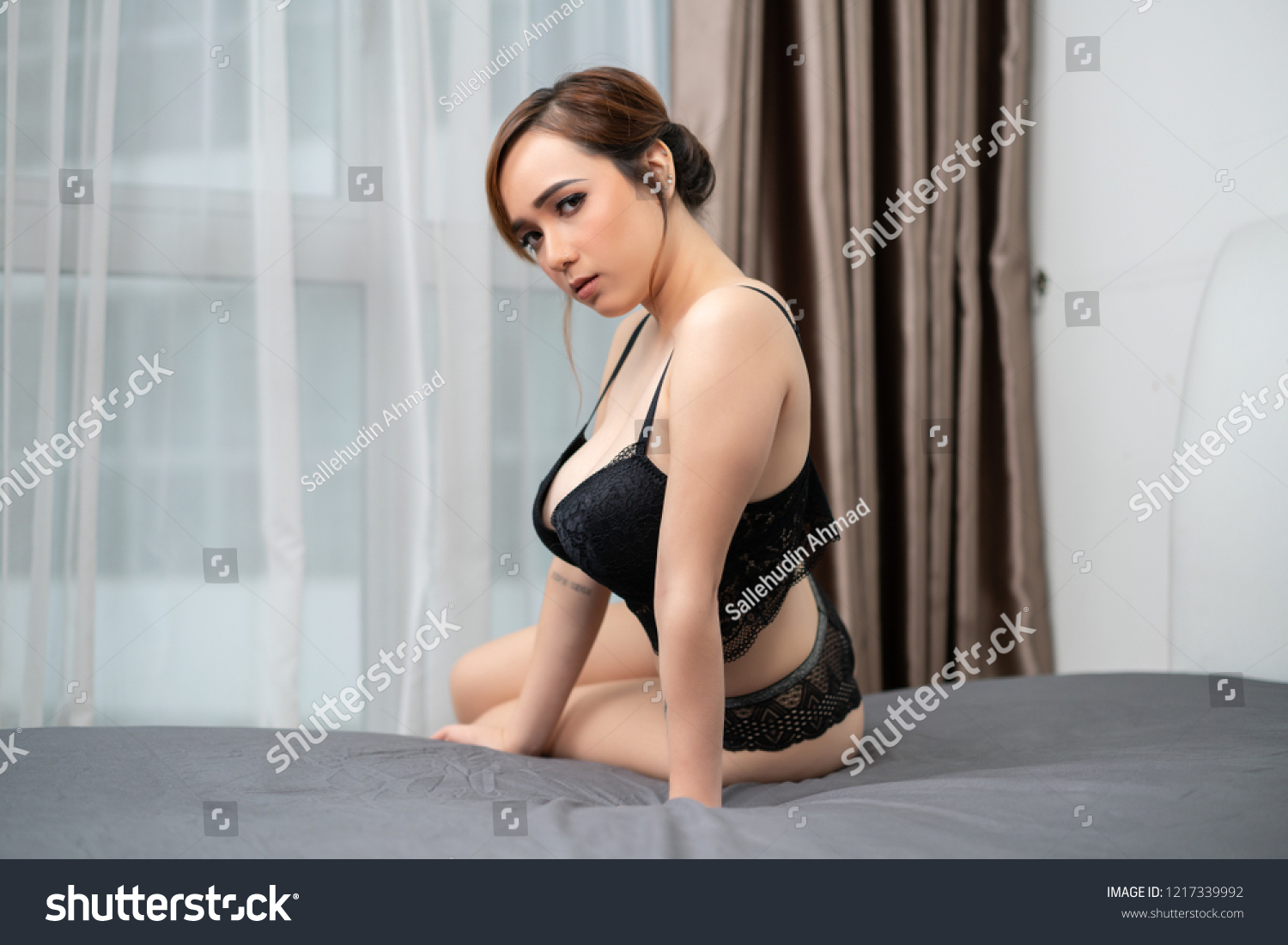 Portrait of gorgeous sexy girl in black lace lingerie posing in a bedroom. Beautiful young girl in a sexy black lingerie. Sexy lingerie concept. #1217339992