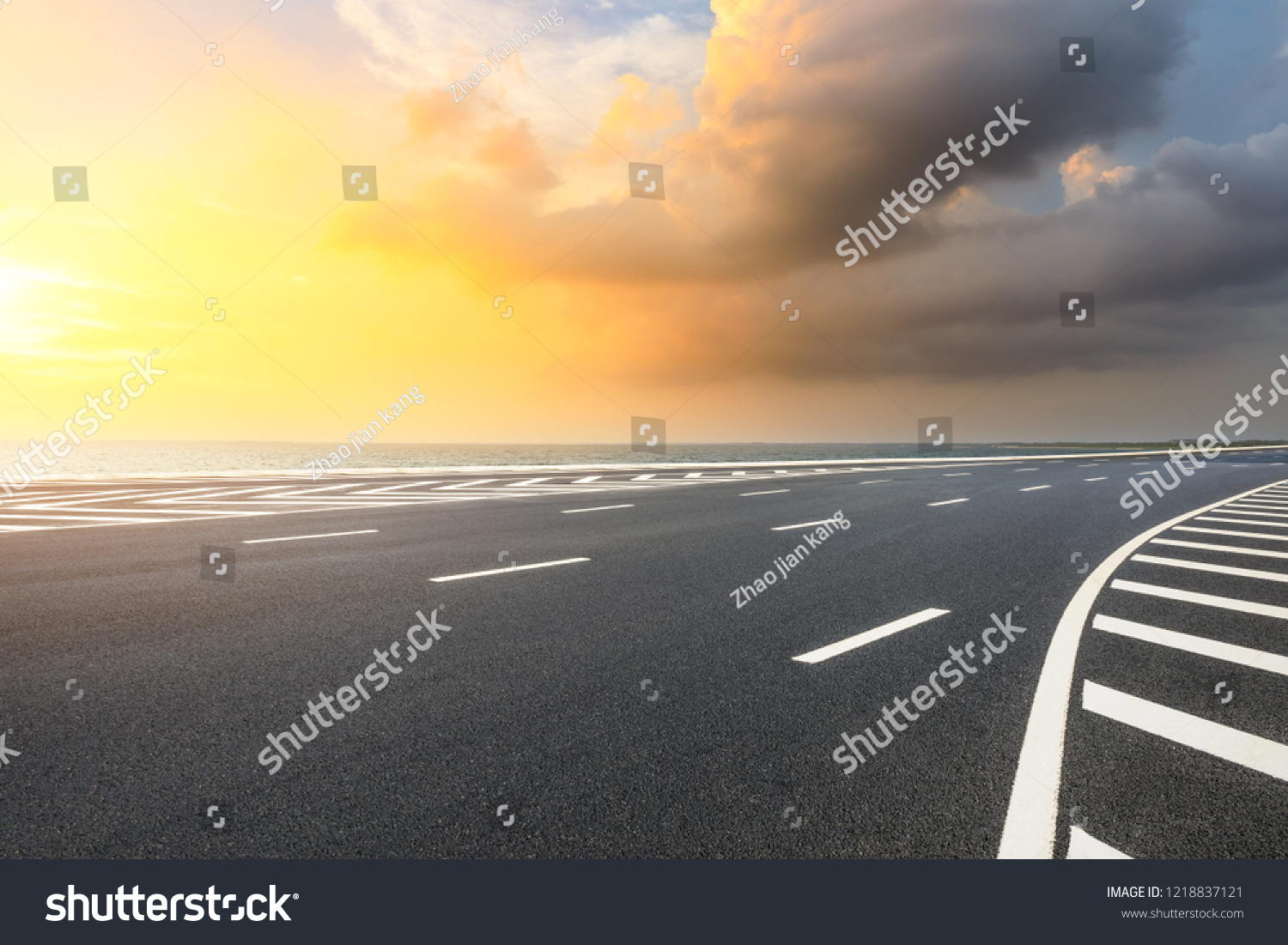 Asphalt road and dramatic sky with coastline at sunset #1218837121