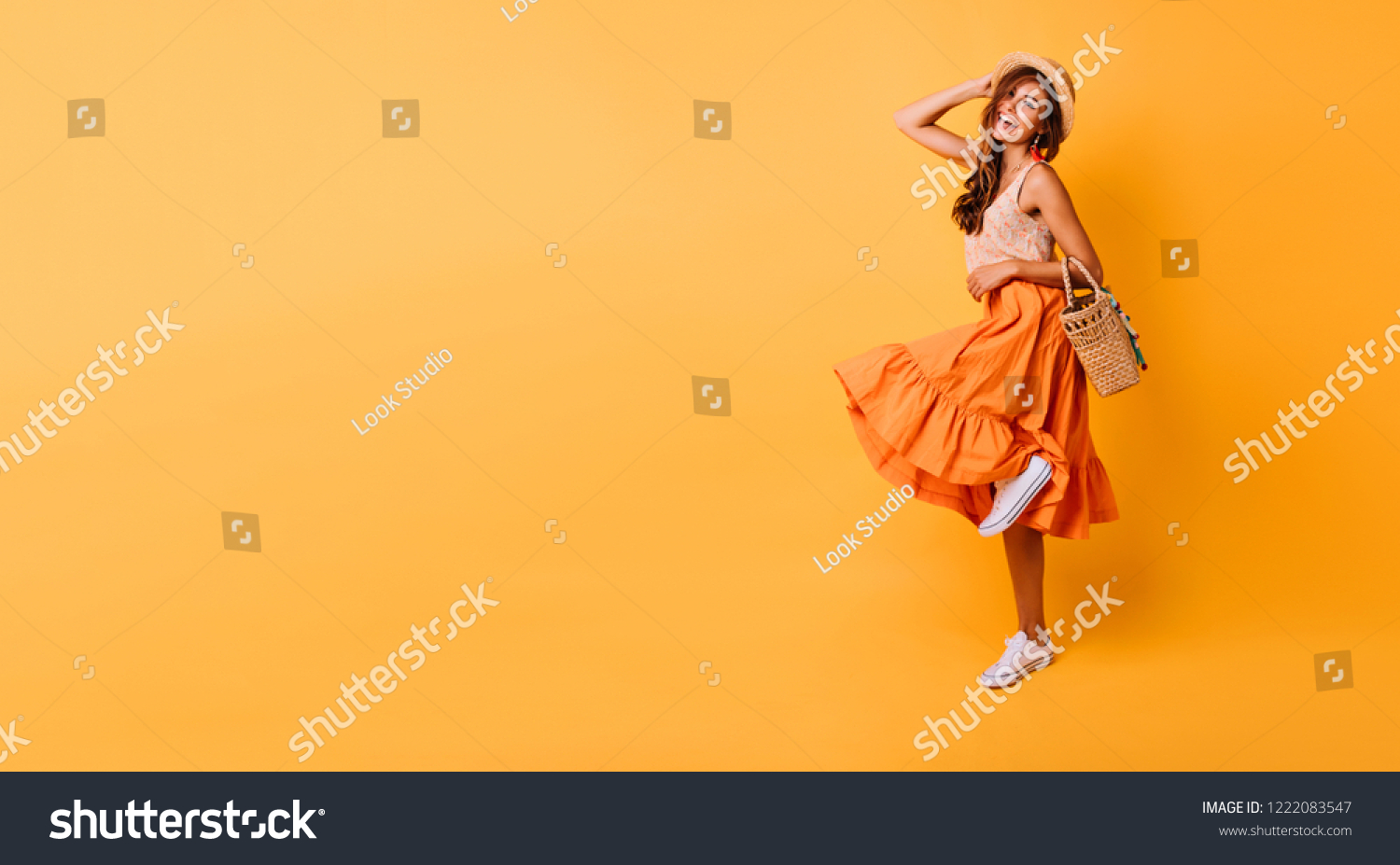Magnificent woman in long bright skirt dancing in studio. Carefree inspired female model posing with pleasure on yellow background. #1222083547